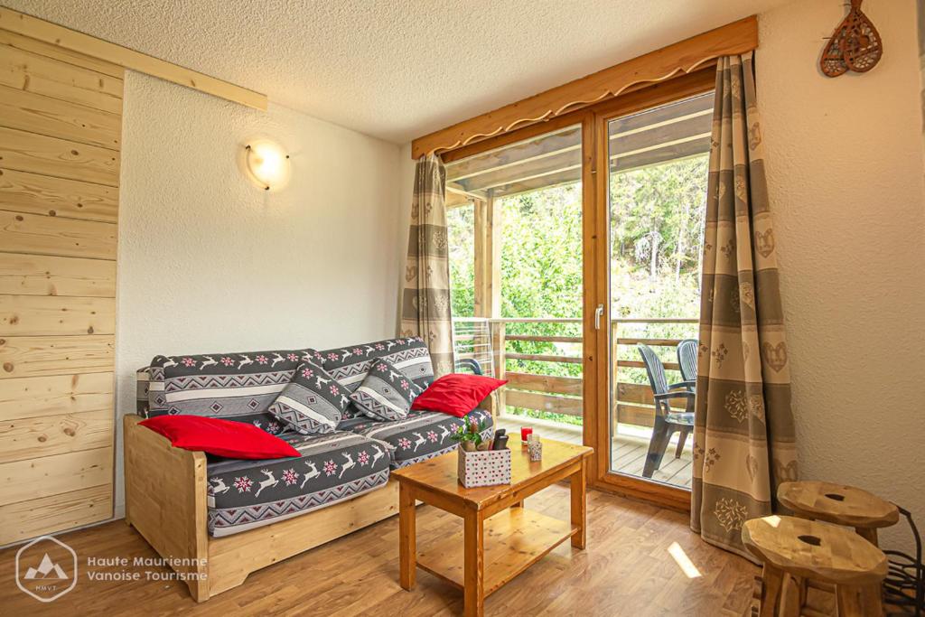 a living room with a couch and a balcony at Le chalet d'Isis in Villarodin-Bourget