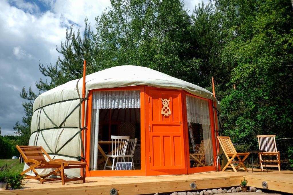 an orange yurt with chairs and a table at Jurta Kołbielska in Podgórzno