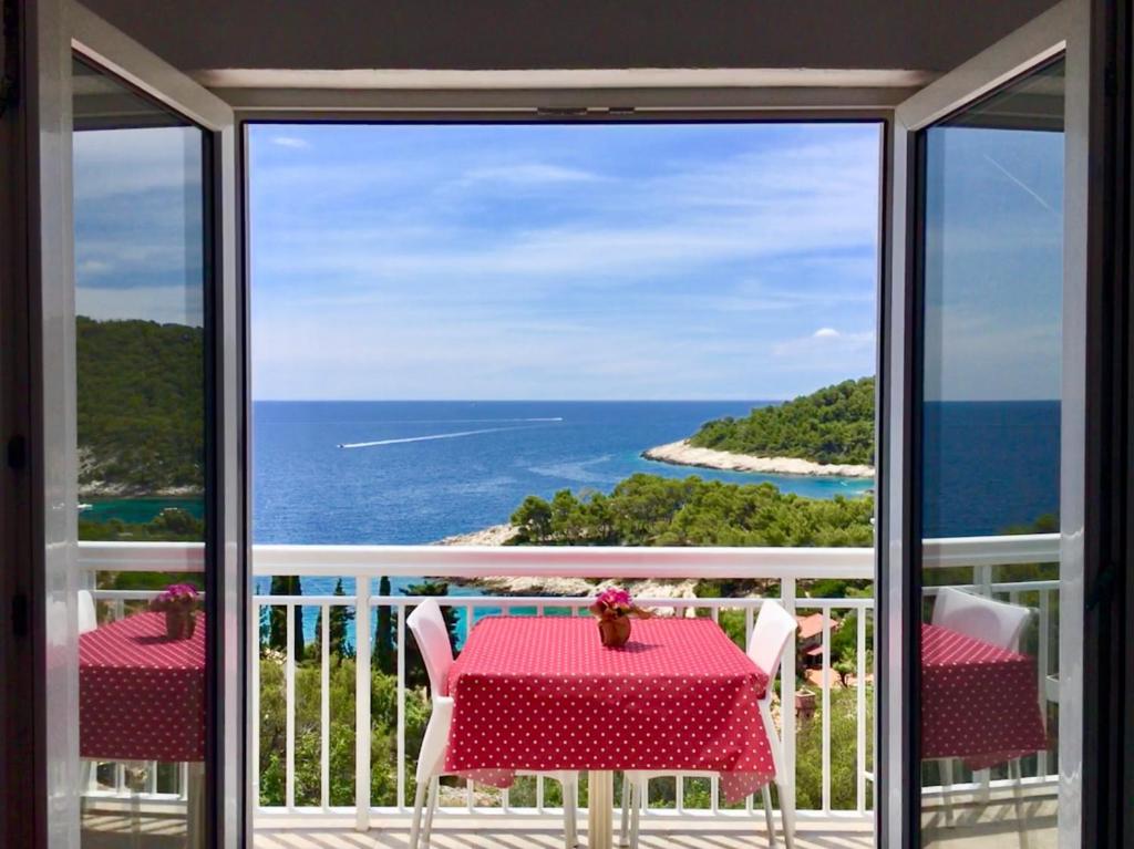 a dining room table with a balcony overlooking the ocean at Apartments Marija Magdalena in Hvar