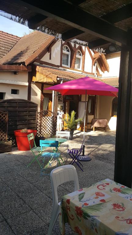 a patio with a table and chairs and an umbrella at Logis Doubs Rivage in Charette
