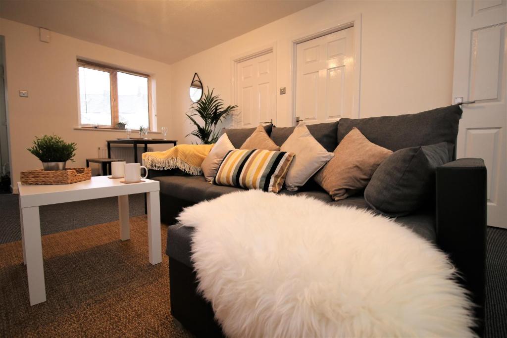 a living room with a black couch with pillows at Thesiger Court Apartments - Free Private Parking - by Property Promise in Cardiff