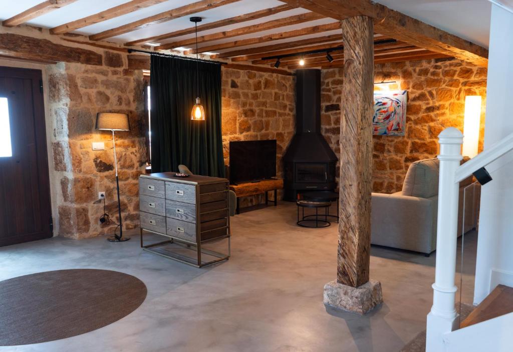 sala de estar con pared de piedra y estufa de leña en Casa Rural Pozo Roñañuela en El Royo