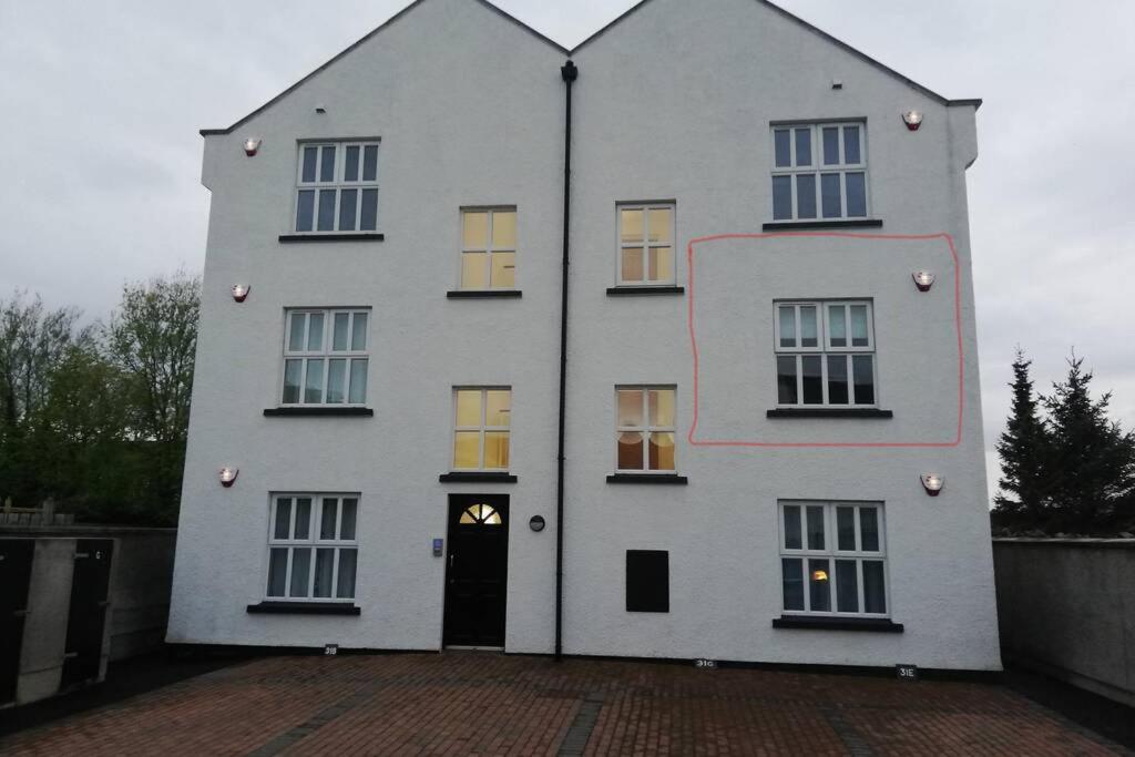a large white building with a black door at Mews Apartment, Bushmills in Bushmills