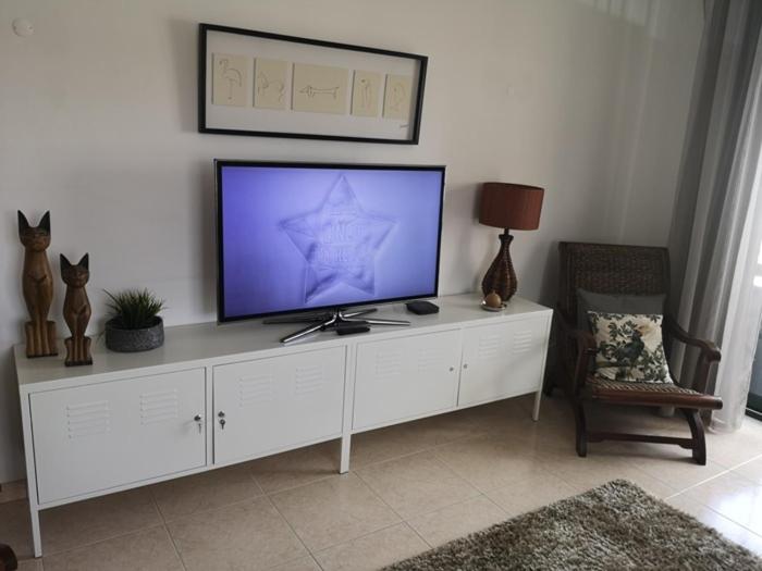 a television on a white cabinet in a living room at Dunas Mar in Alvor