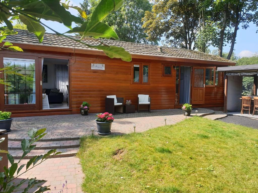 uma casa de madeira com um pátio e um quintal em Urbane Holiday Home in Garderen with Terrace and Garden em Garderen