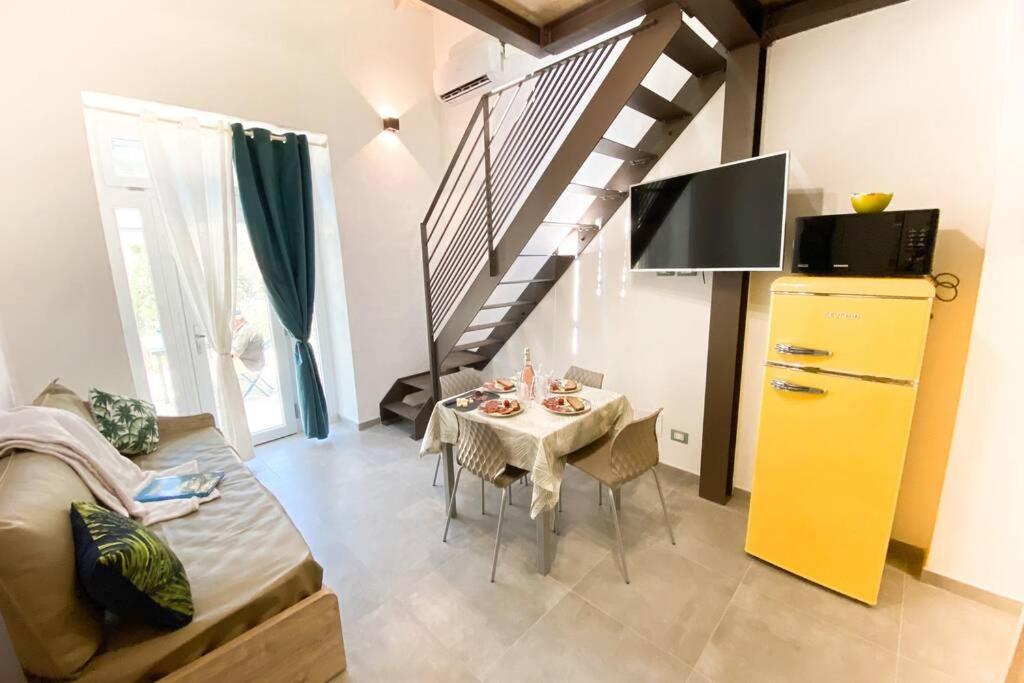 salon ze stołem, telewizorem i schodami w obiekcie New Agriloft 4 Palms clima, giardino e Wi-Fi a 50 mt dal mare w mieście Bordighera