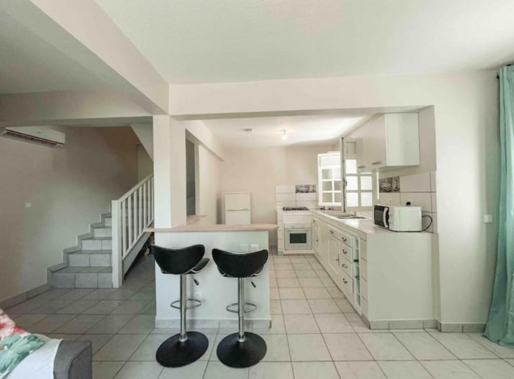 a kitchen with two black stools in a room at VILLAS AUMIS 2MR in Fort-de-France