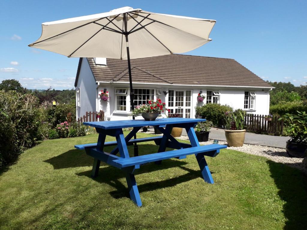 a blue picnic table with an umbrella in front of a house at O' Sullivan's B & B in Killarney