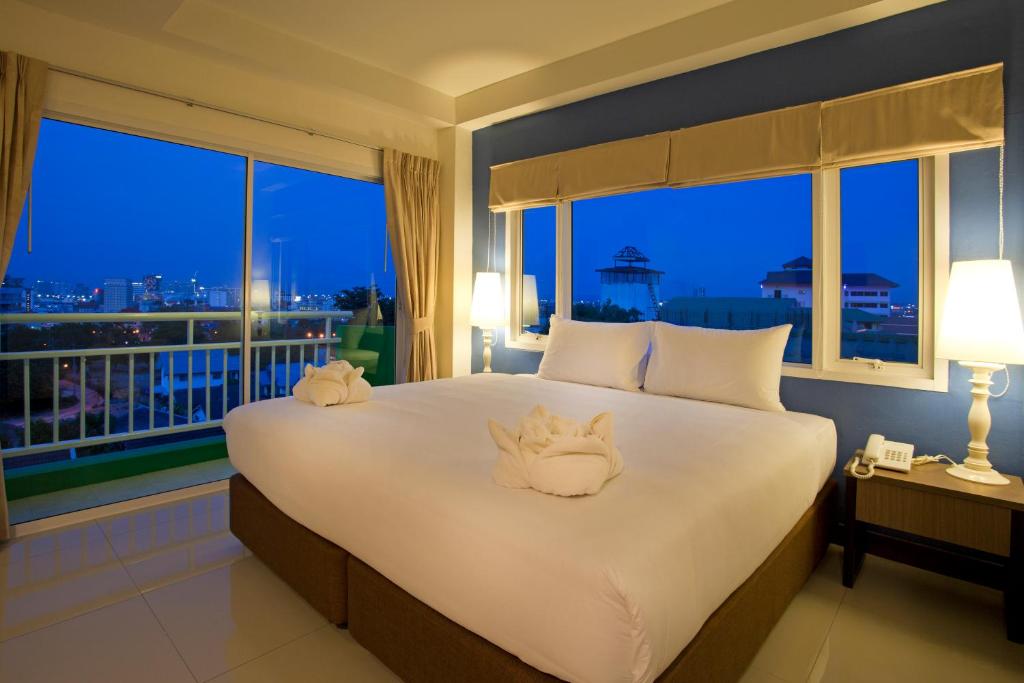 Un dormitorio con una cama grande con una ventana grande. en Wiz Hotel, en Pattaya South