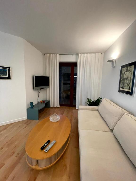 a living room with a white couch and a wooden table at Apartament Jurata 30 in Jurata