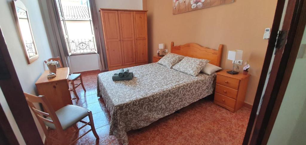 een slaapkamer met een bed, een bureau en een stoel bij la casita de julia, pobla llarga in Puebla Larga