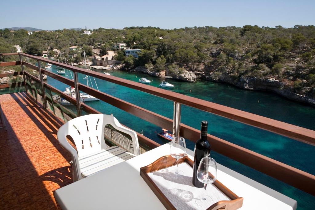 uma mesa com uma garrafa de vinho na varanda em Apartamentos Llevant em Cala Figuera