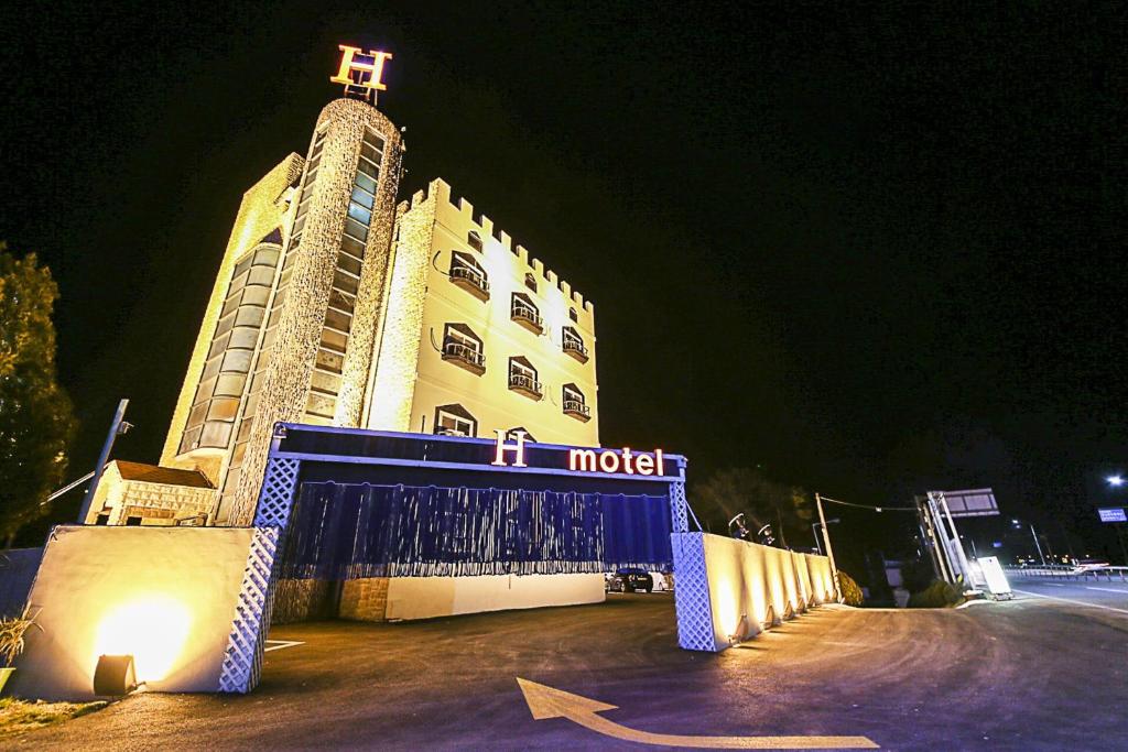 um hotel com uma cruz em cima à noite em H Motel em Gongju