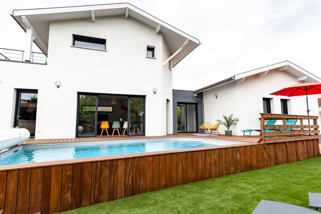 uma casa com uma piscina e uma cerca de madeira em Frenchyhomes☆villadeluxe☆Plage☆piscine em Andernos-les-Bains