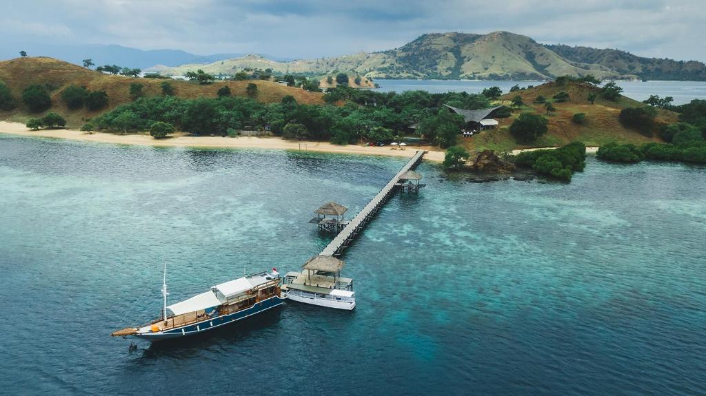 a boat in the water next to an island at The Seraya Resort Komodo in Labuan Bajo