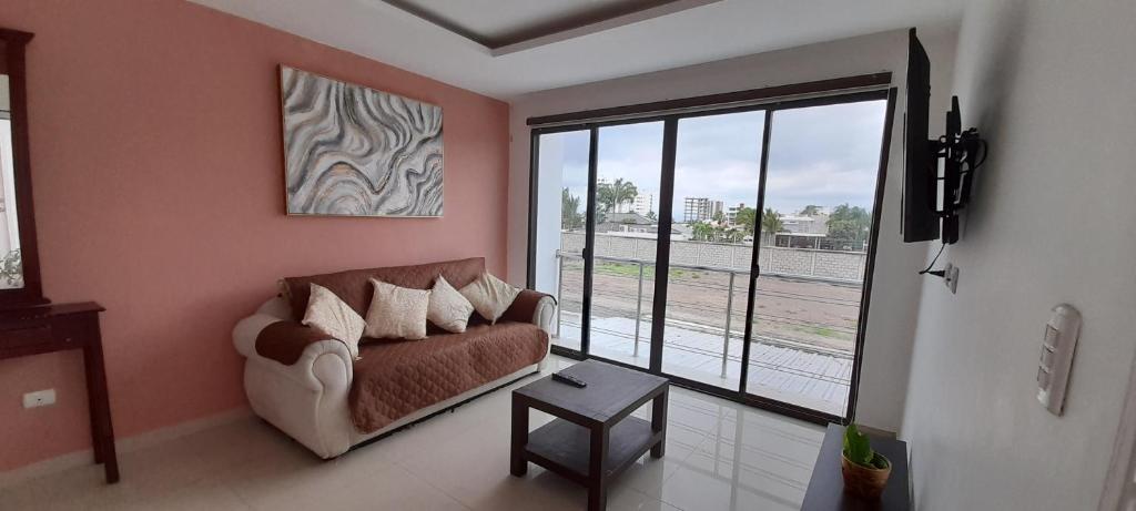 a living room with a couch and a large window at Espectacular departamento de tres habitaciones en Edificación Amaralto in Manta
