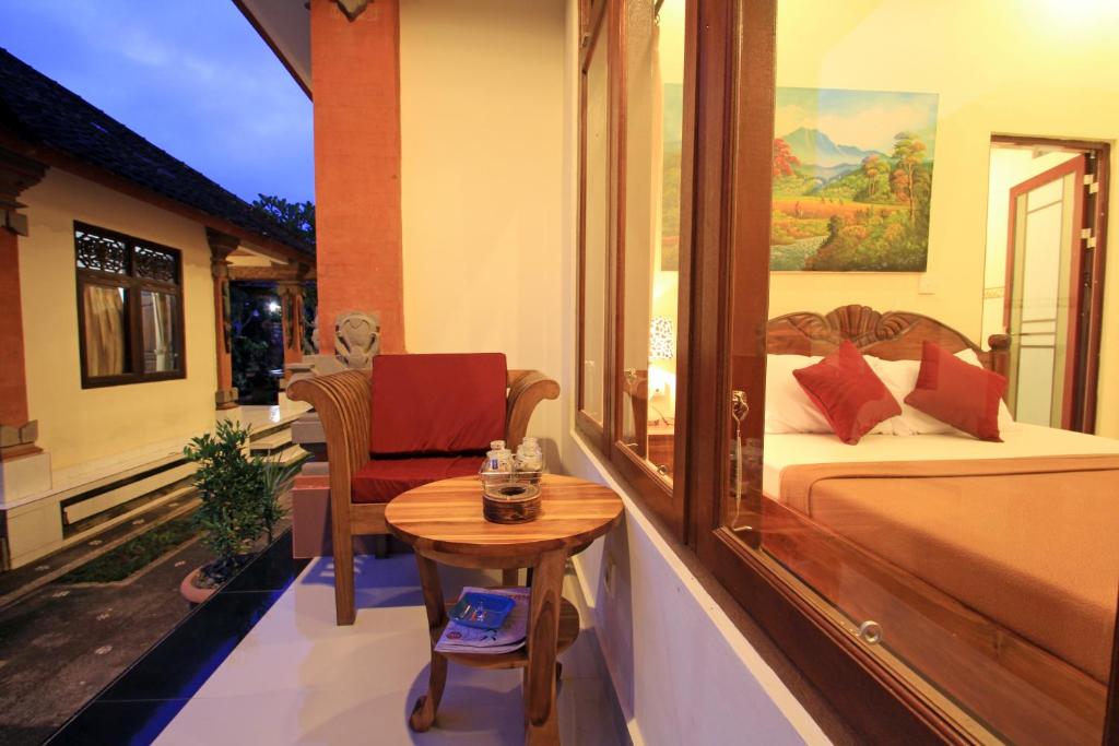 a bedroom with a bed and a table and a chair at KT. Kuaya Home Stay in Ubud