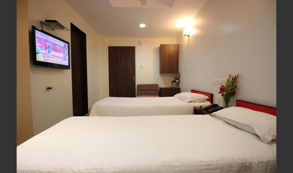 a hotel room with two beds and a flat screen tv at Hotel Airlines International in Mumbai