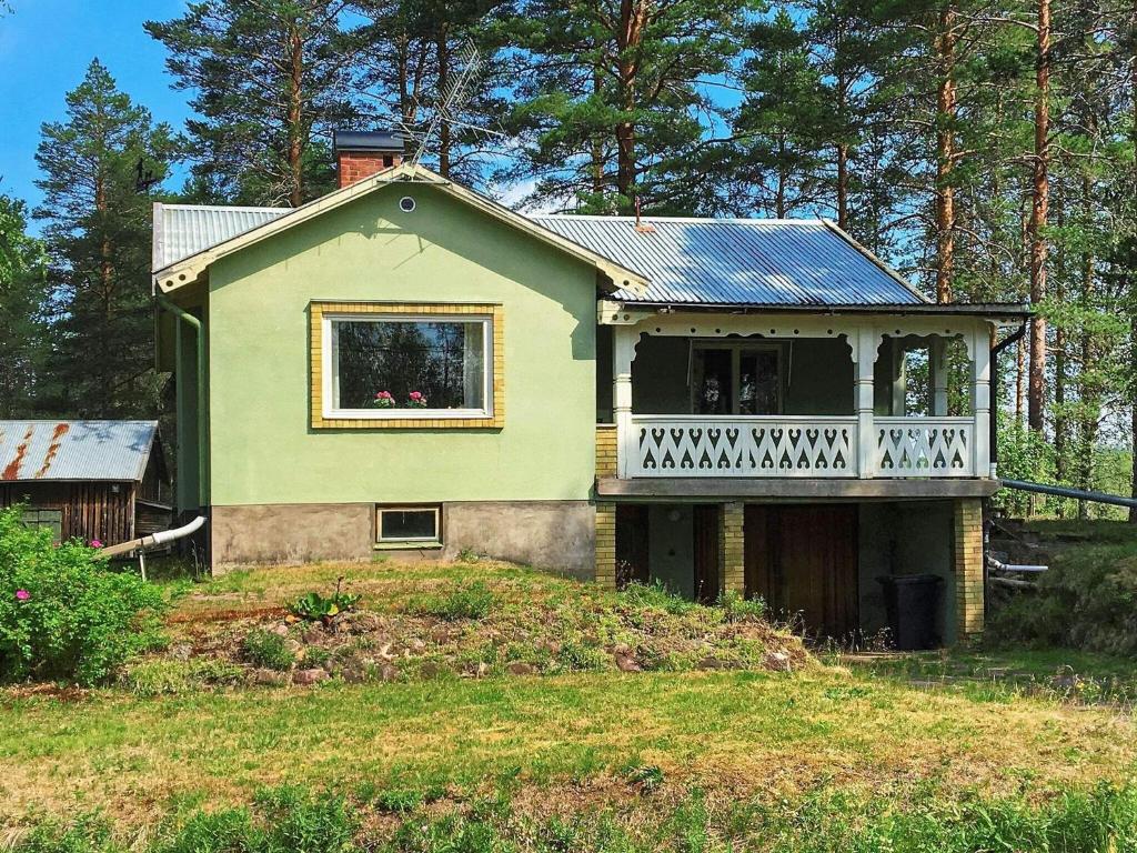 a green house with a balcony on top of a yard at Holiday home RÖRBÄCKSNÄS in Rörbäcksnäs