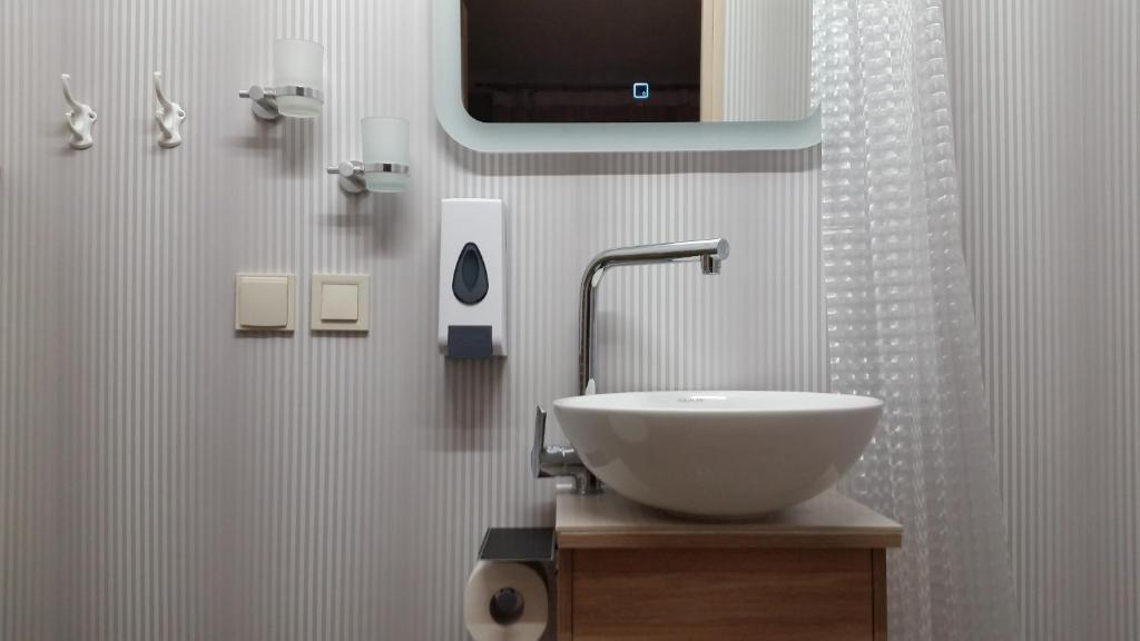 baño con lavabo y TV en la pared en Baltā, en Ventspils