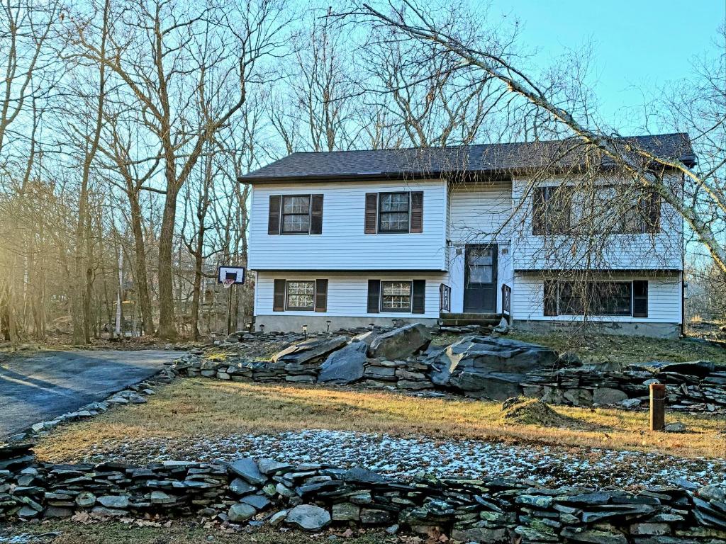 una antigua casa blanca con una pared de piedra en The Pocono's Retreat with a Gameroom, Firepit, and Lake en Bushkill