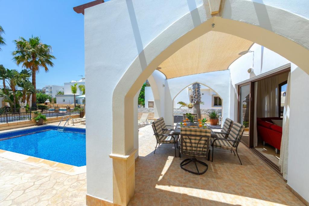 a patio with a table and chairs next to a swimming pool at Protaras Villa Elena 3 in Protaras