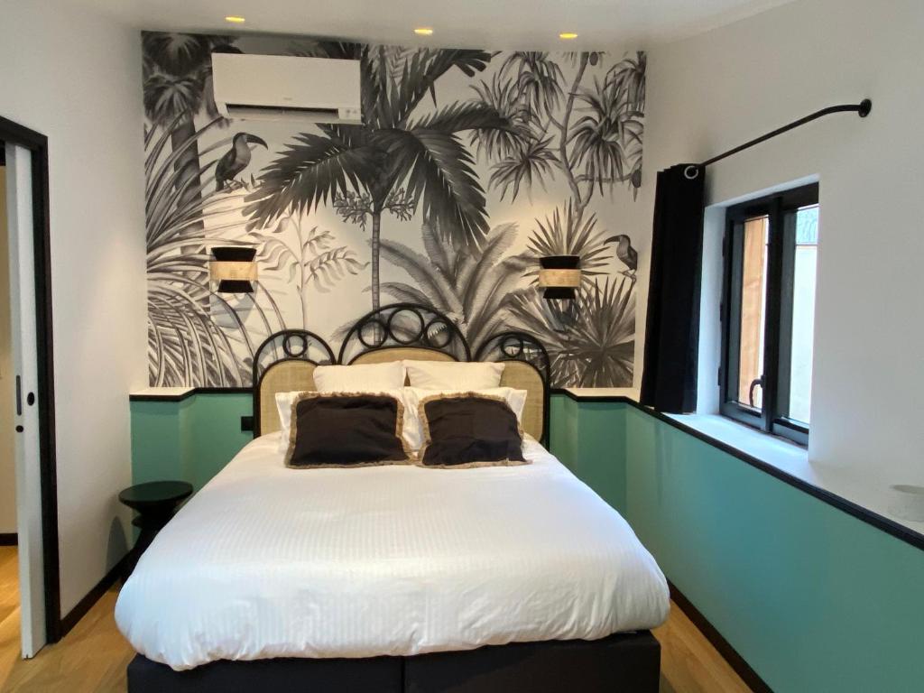 - une chambre avec un lit et du papier peint en palmier dans l'établissement La Terrasse Sainte Catherine, à Bordeaux