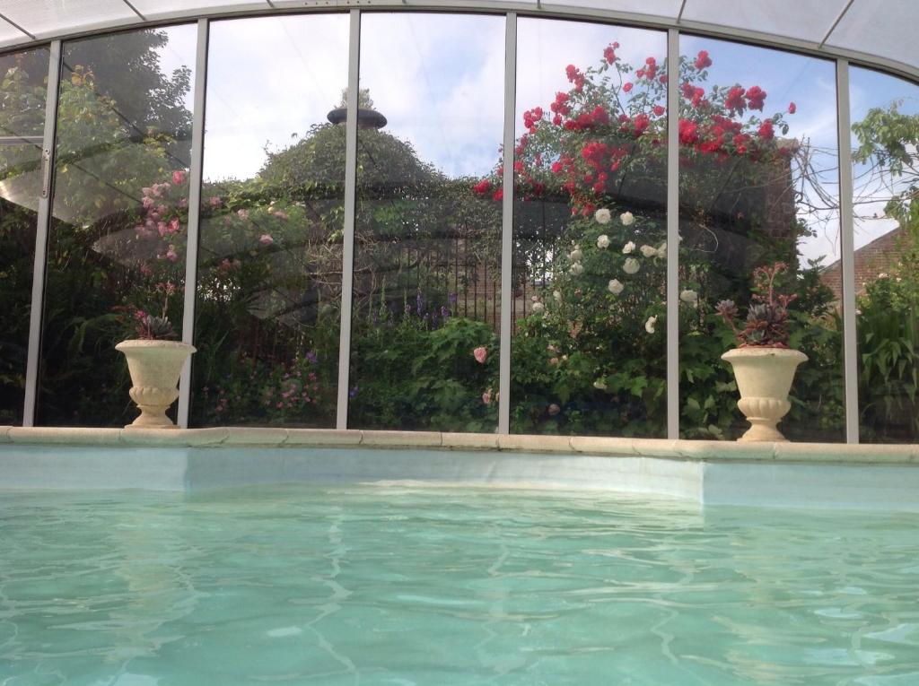 una piscina frente a un edificio con flores en B&B La demeure du Papillon, en Mouscron