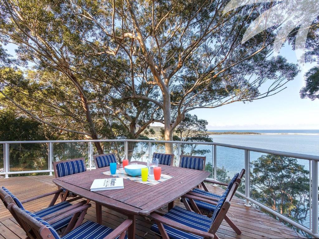 a wooden table with chairs on a deck with the ocean at Sandbar View in Smiths Lake