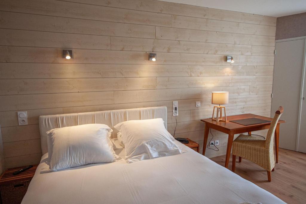 1 dormitorio con cama blanca y pared de madera en lhotel en Thouars
