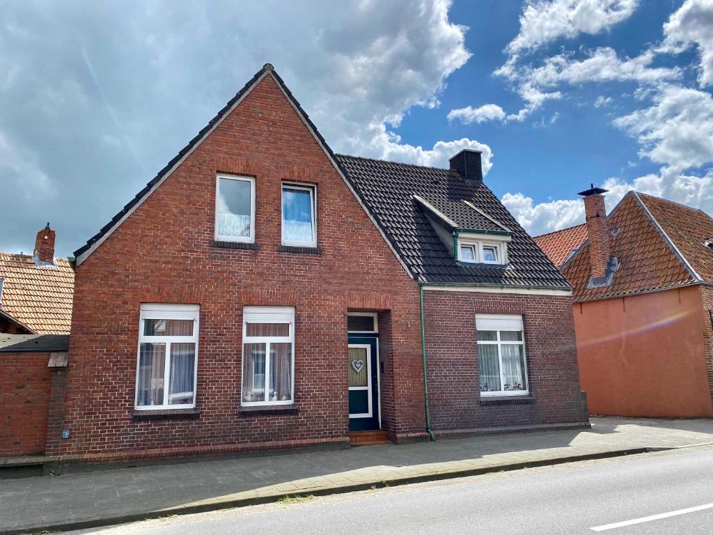 a red brick house with white windows on a street at Ferienwohnungen Alte Maar 65330 in Moormerland