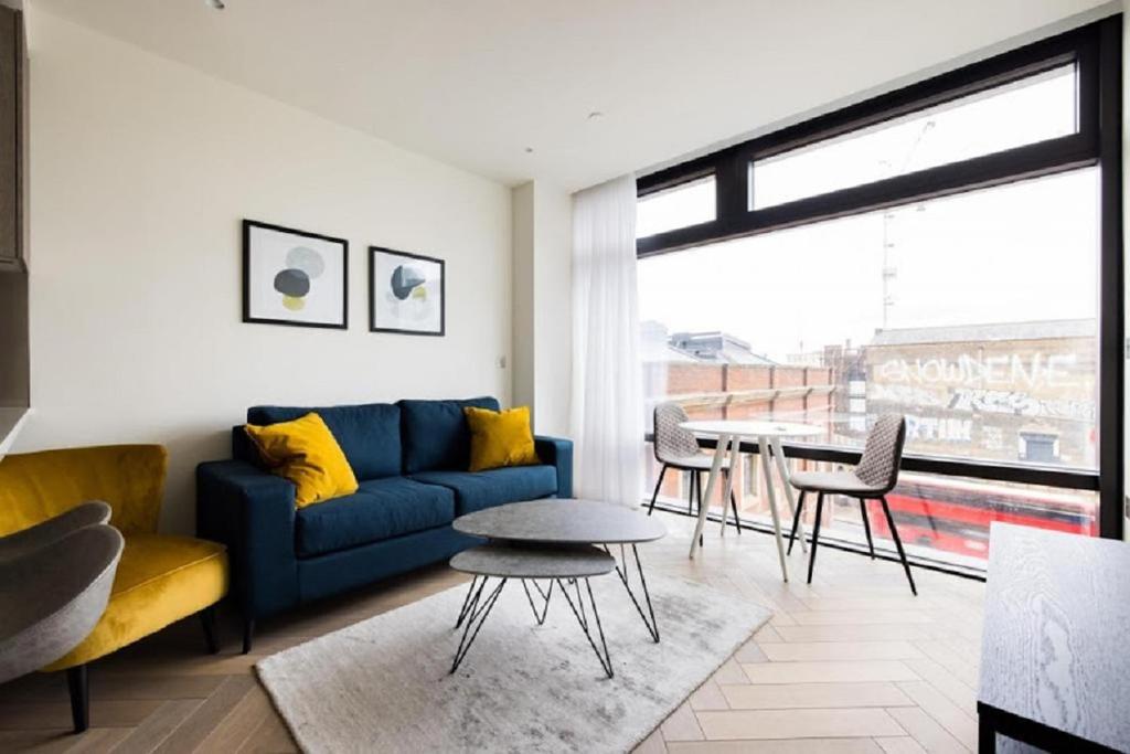 Premium Apartment near Liverpool Street Station في لندن: غرفة معيشة مع أريكة زرقاء وطاولة