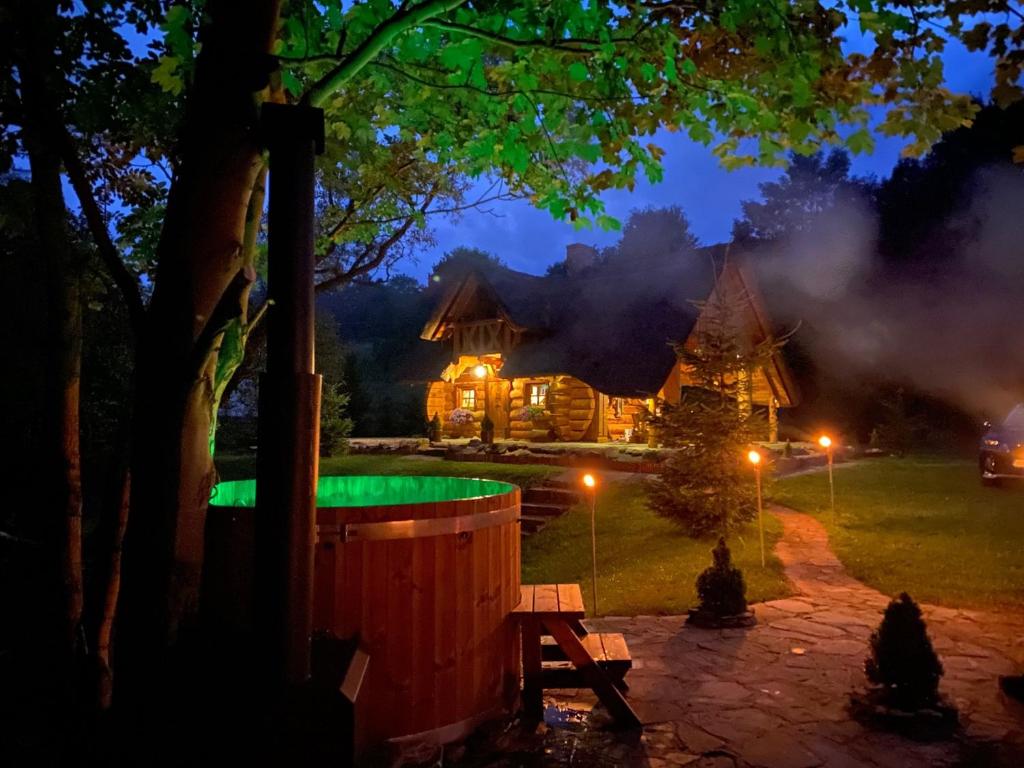 domek z bali w nocy z zielonym basenem w obiekcie Domek Szyjówka w mieście Chyrowa