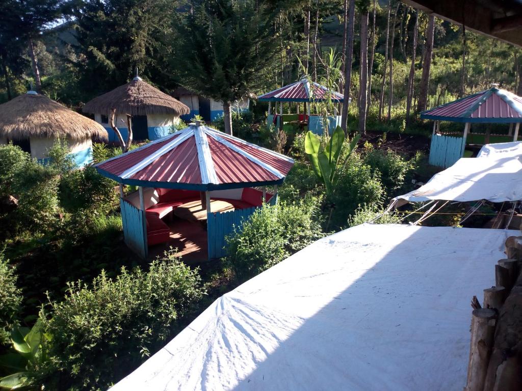 a garden with a small house with a roof at Maverick Camp, Rondavels and Homestay in Nyandarua 