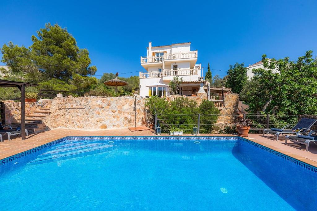 a villa with a swimming pool in front of a house at Villa Sol in Cala Figuera