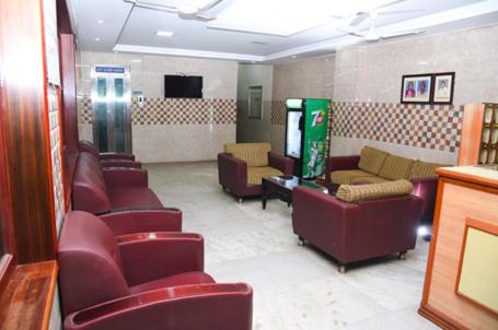 a waiting room with couches and chairs and a tv at Hotel Radhakrishna in Madurai