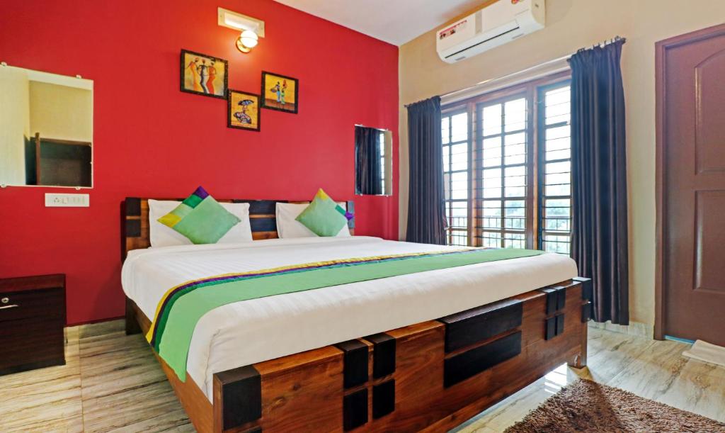 a bedroom with a large bed with red walls at Treebo Trend Avyukta Stay in Madikeri