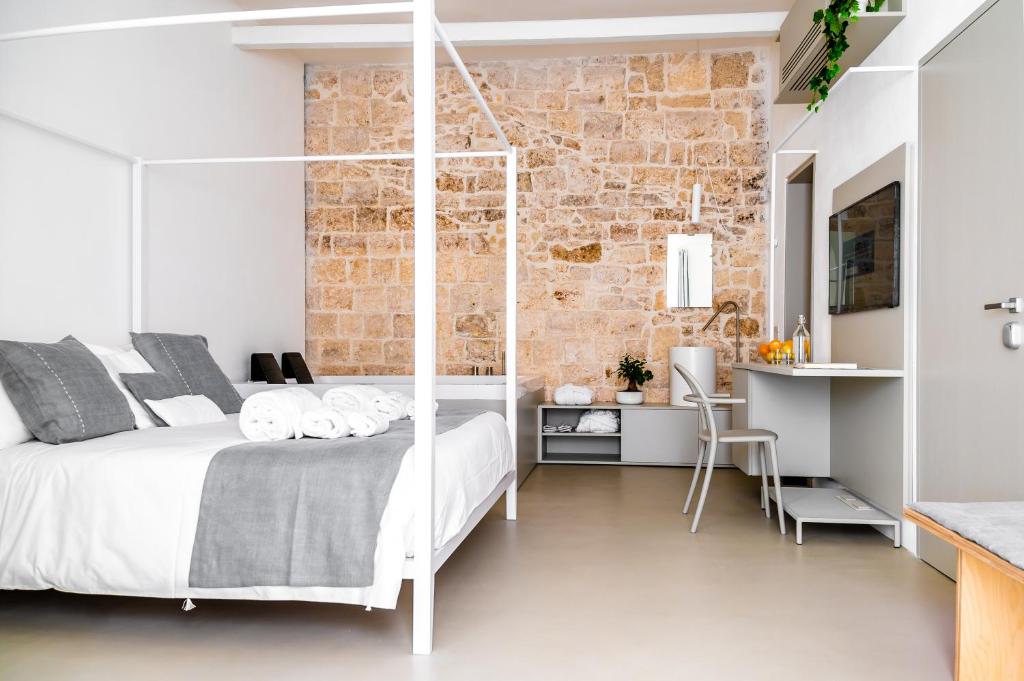 a bedroom with a white bed and a brick wall at Tre Archi Suite & Relais in Polignano a Mare