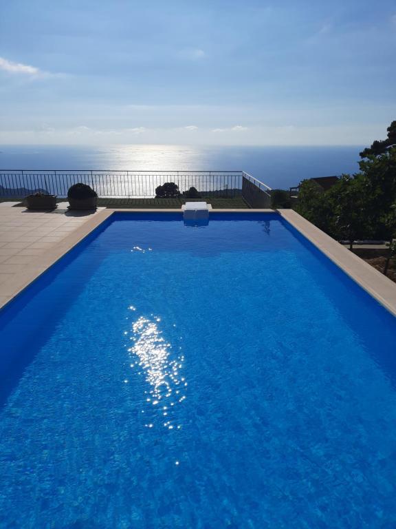 a blue swimming pool with the ocean in the background at The Sunset Villas Kefalonia in Kothréas