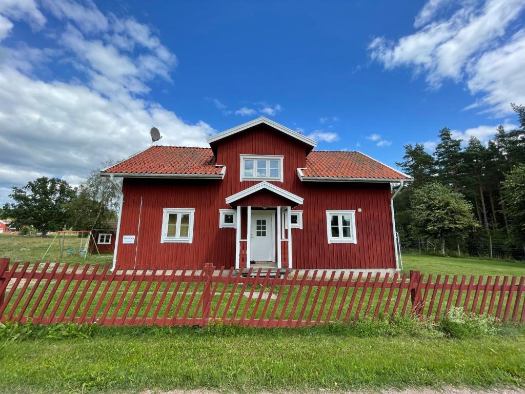 une maison rouge avec une clôture rouge devant elle dans l'établissement Humpen, Hultåkra, à Mariannelund