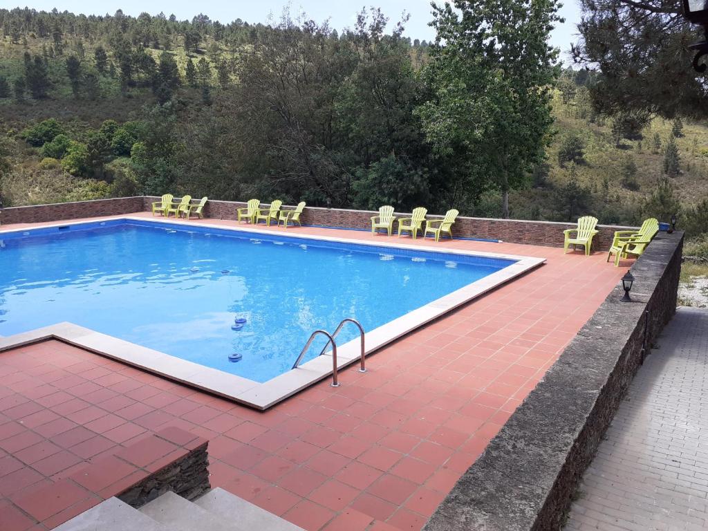 a large swimming pool with yellow chairs at Quinta Das Lameirinhas in Marvão