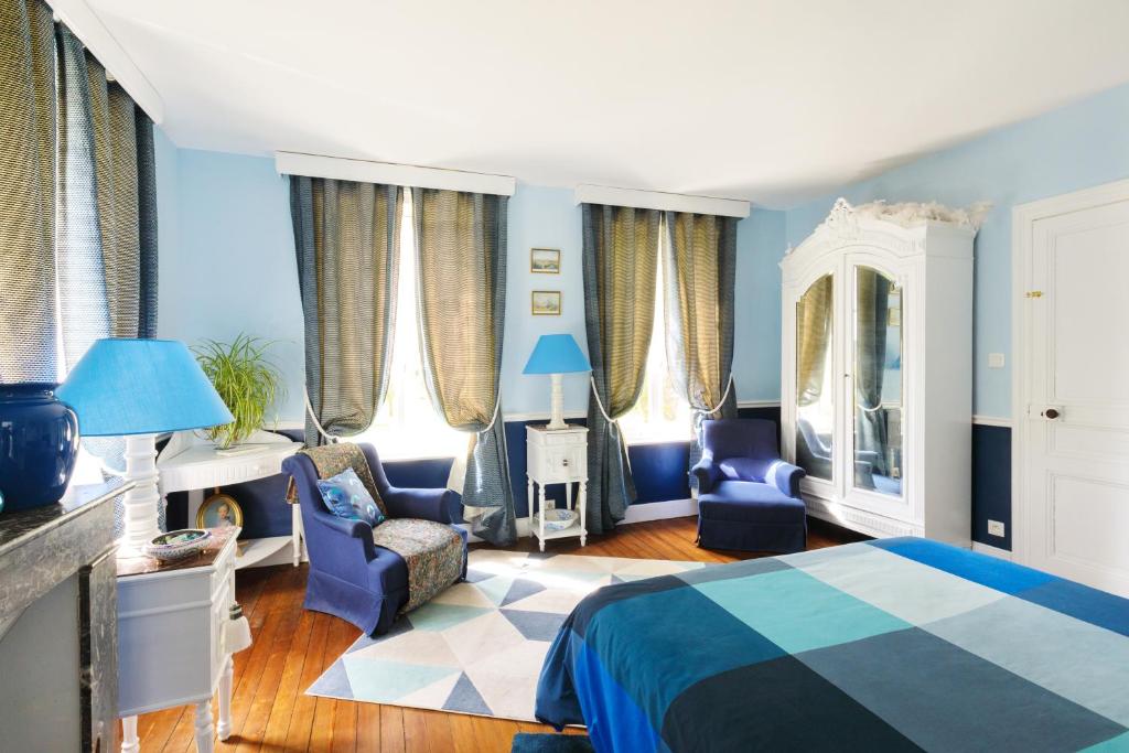 1 dormitorio con paredes azules, 1 cama y sillas en Manoir du Clap, en La Cerlangue