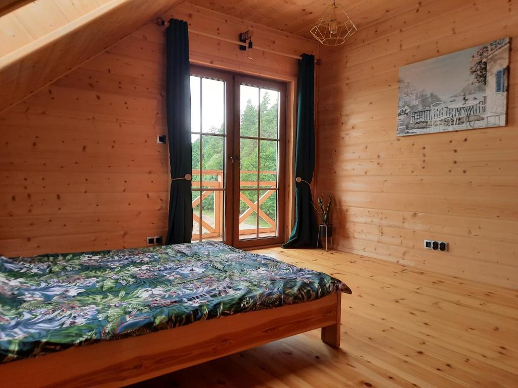 a bedroom with a bed and a window in a log cabin at Willa Kaszubiak in Ostrzyce