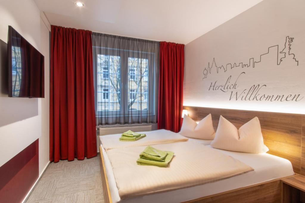 a bedroom with two beds with red curtains at Hotel Wettiner Hof in Riesa