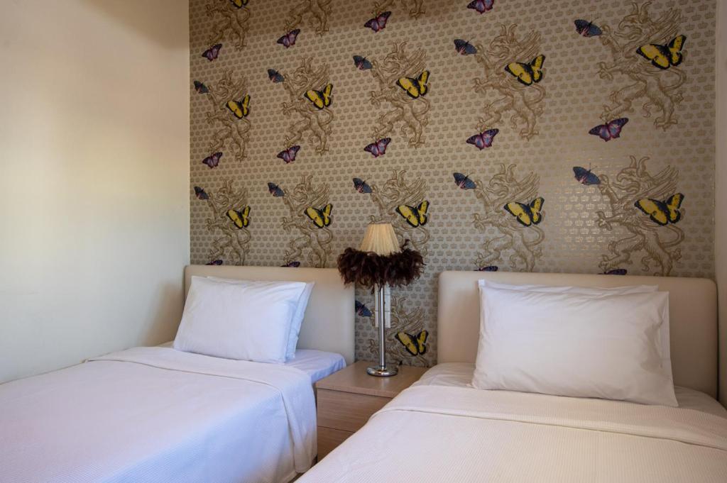 two beds in a room with butterflies on the wall at White Crystal Beachfront Apartment in Gournes