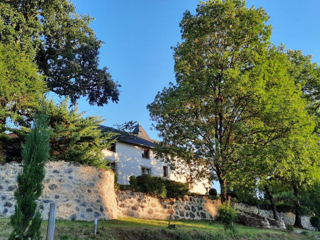 a house behind a stone wall with trees at Manoir XV Domaine de Peyrafort in Tulle