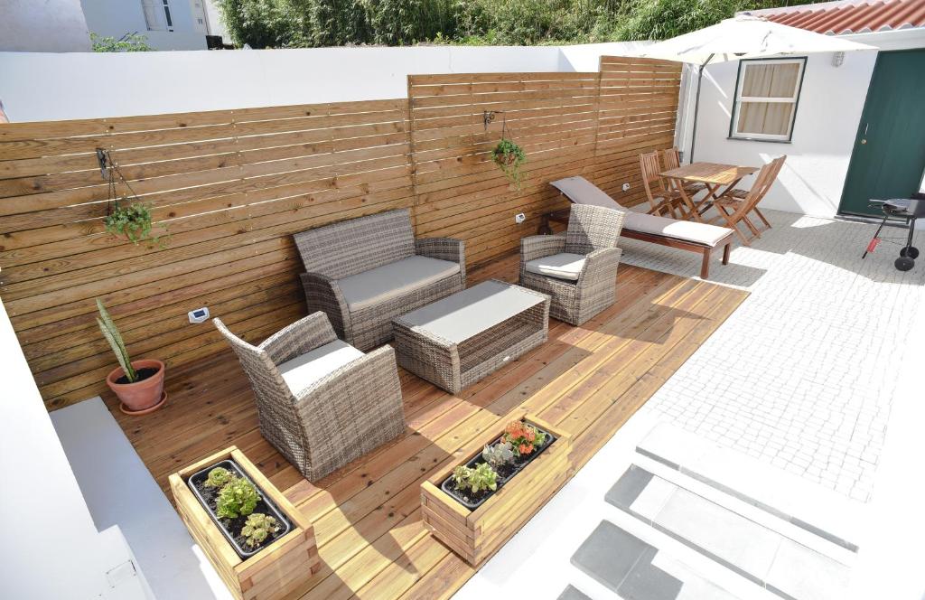 eine Terrasse mit Korbmöbeln und einem Holzzaun in der Unterkunft Dabneys Studio in Horta