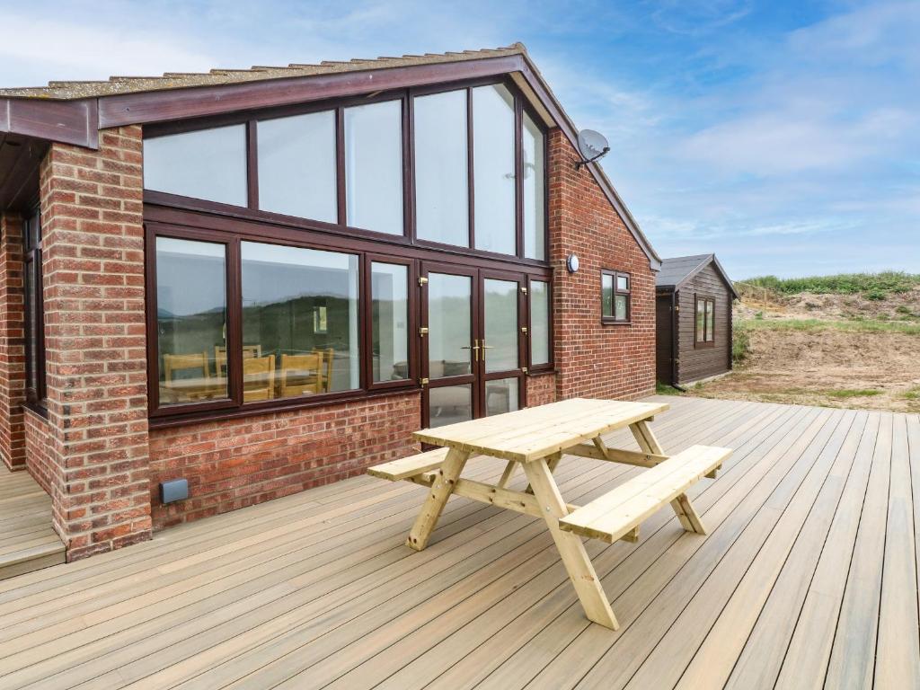 a wooden deck with a picnic bench on top of a building at Windyridge in Norwich