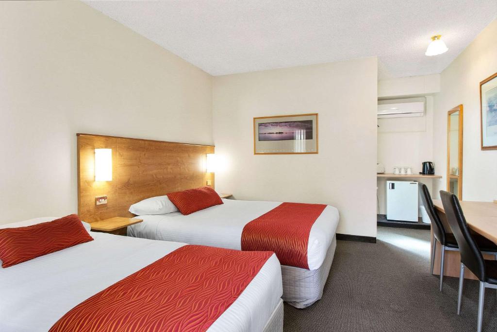 a hotel room with two beds and a desk at Econo Lodge Griffith Motor Inn in Griffith