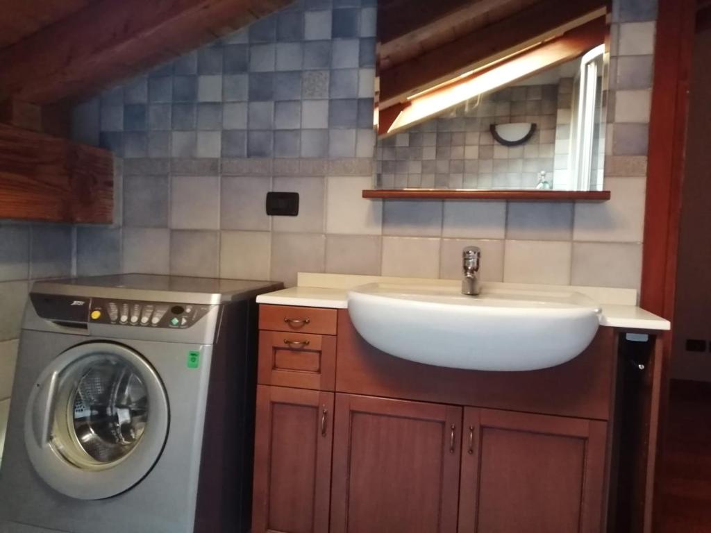 a bathroom with a sink and a washing machine at Mansarda Chanoux CIR n 0027 in Châtillon